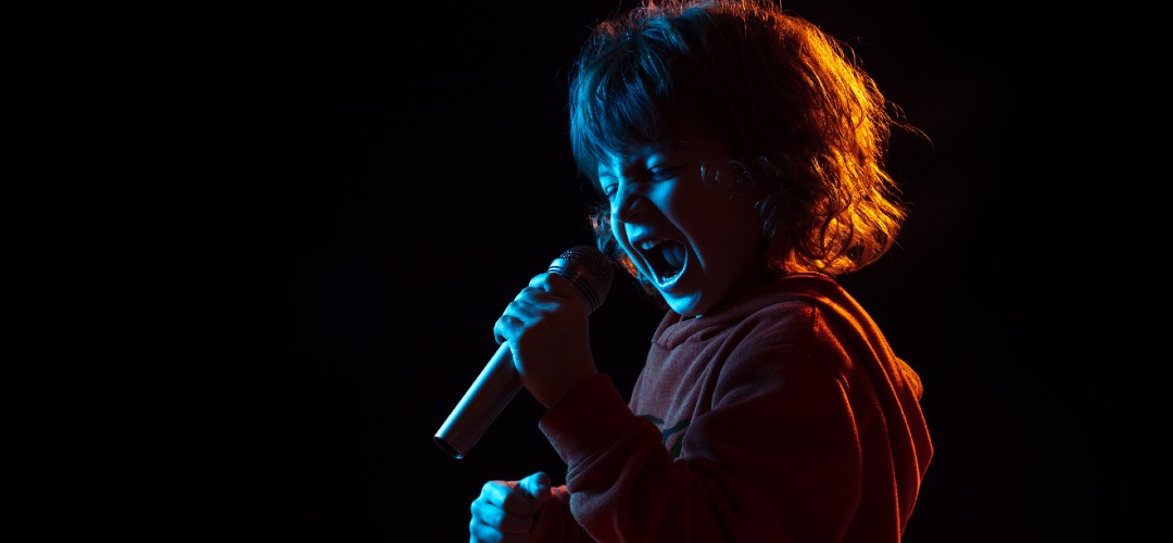 mikrofonla şarkı söyleyen küçük çocuk